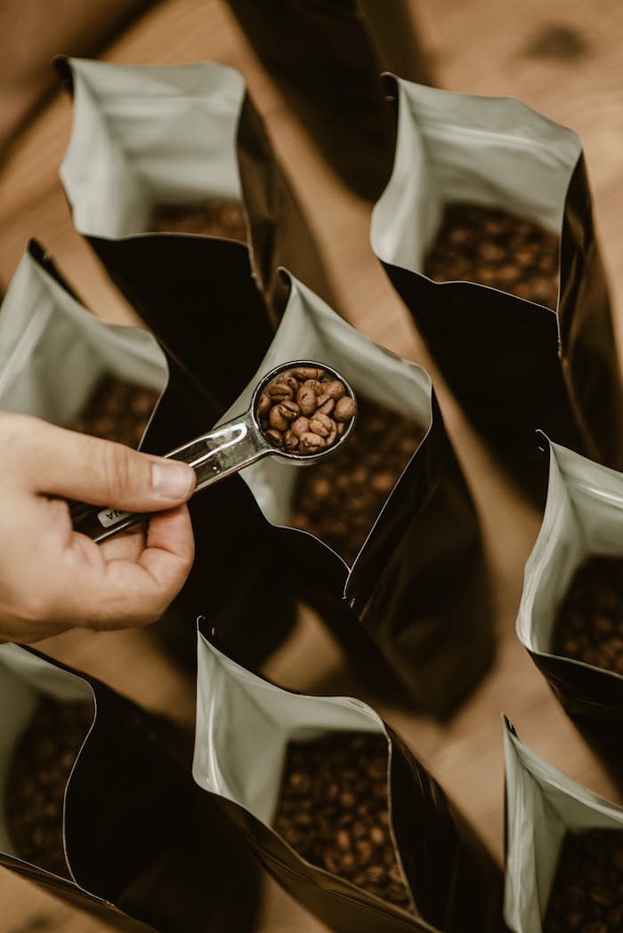 A person scooping coffee beans into bags, emphasizing fresh roasting and packaging.